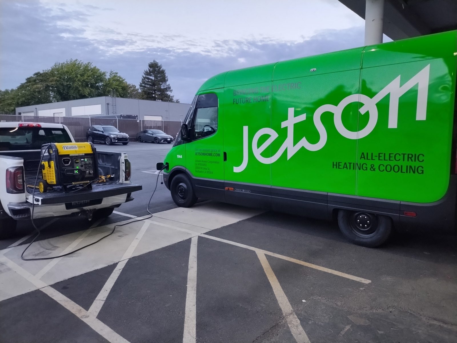 Electric delivery van charging in a commercial lot from a truck-mounted mobile charger